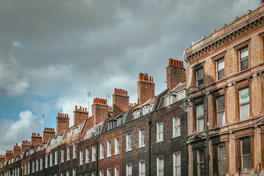 Roofline of a London Georgian terrace, with dormer windows and groups of chimney pots against a cloudy sky